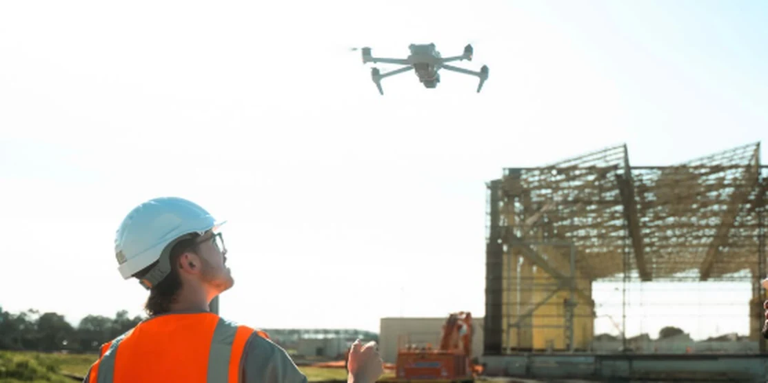 Site worker in a hard hat and hi-vis flying a drone over a Melbourne construction site